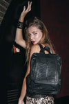 Woman wearing a black textured backpack against a dark background